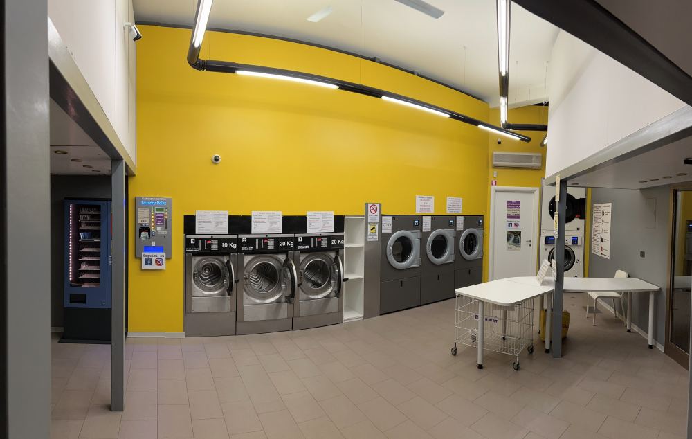 La sala della lavanderia Wash in The City di Via Milano, con lavatrici e asciugatrici professionali